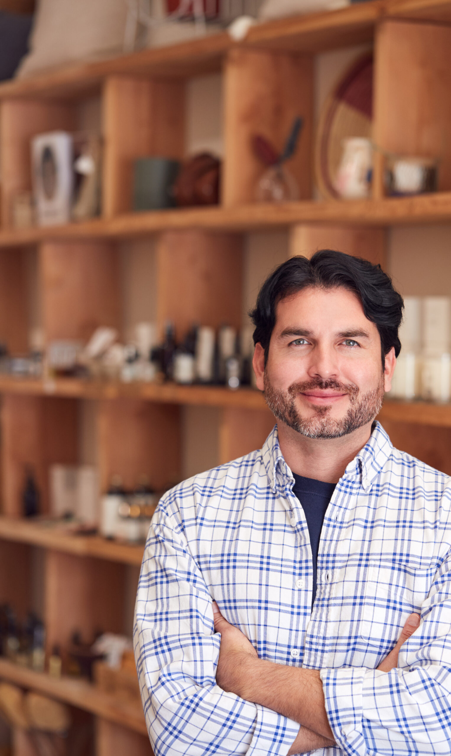Portrait Of Male Owner Of Gift Store Standing In Front Of Shelves With Cosmetics And Candles